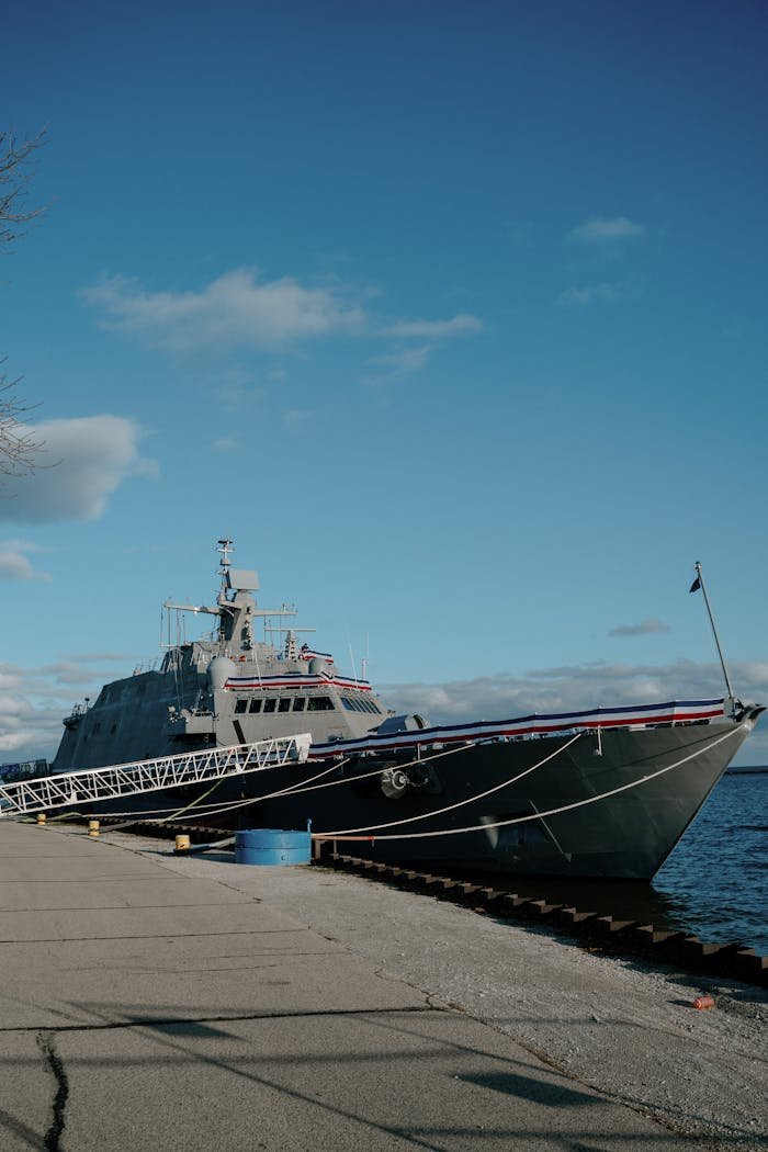 A naval ship docked at Milwaukee's waterfront on a bright day with clear skies.